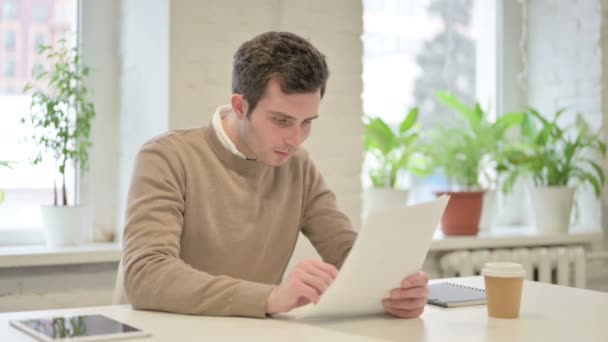 Чоловік читає звіти сидячи в офісі — стокове відео