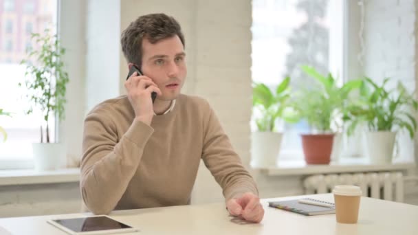 Чоловік говорить на смартфоні в офісі — стокове відео