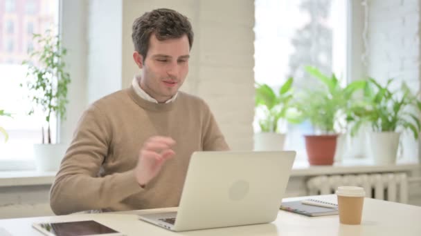 Hombre hablando en videollamada en el ordenador portátil en la oficina — Vídeos de Stock