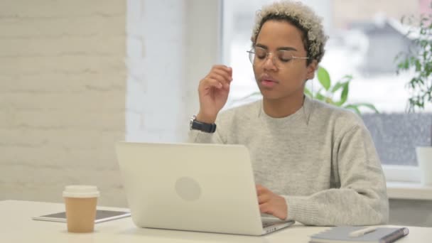 Mujer africana pensando mientras trabaja en el ordenador portátil en la oficina — Vídeos de Stock