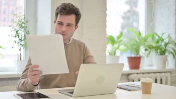 Людина з ноутбуком читання документів в офісі — стокове відео