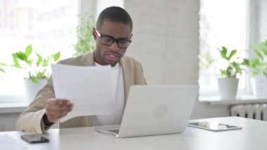 Dizüstü bilgisayarlı Afrikalı Ofiste Belgeler Okuyor 