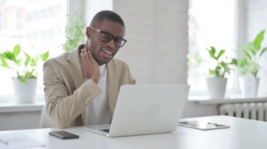 Ofiste dizüstü bilgisayar kullanırken boynu ağrıyan Afrikalı adam 