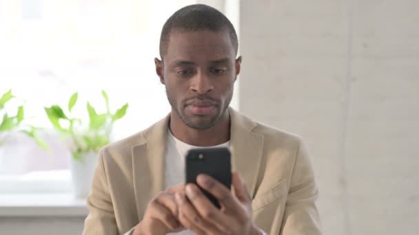 Portret van Afrikaanse Man reageert op verlies op Smartphone — Stockvideo