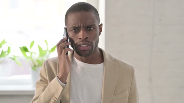 Портрет афроамериканца, раздраженно разговаривающего по телефону — стоковое видео