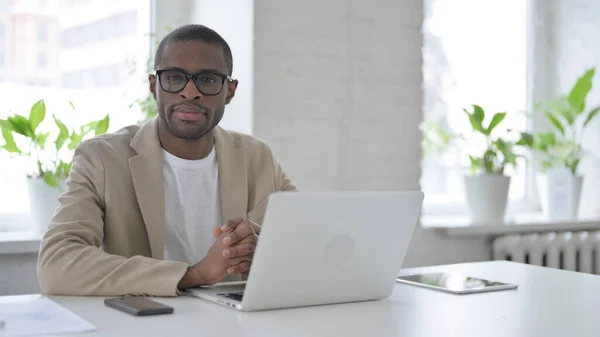 African Man Looking at Camera while using Laptop in Office — Stockfoto