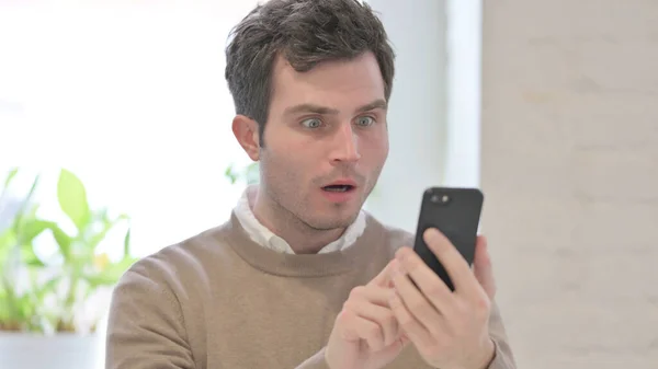 Porträt eines Mannes, der auf Verlust mit dem Smartphone reagiert — Stockfoto