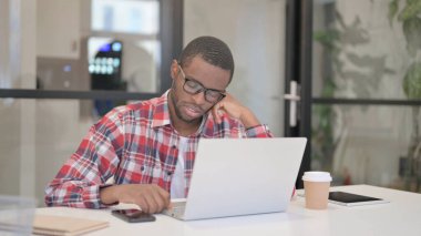 Ofiste dizüstü bilgisayarla oturan yorgun Afrikalı Adam