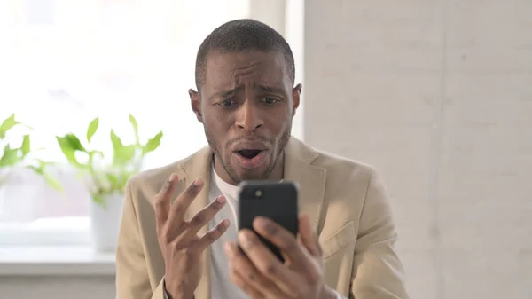 非洲男子在智能手机上对损失的反应的肖像 — 图库照片