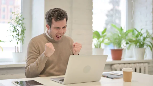 Homem comemorando o sucesso ao usar o portátil no escritório — Fotografia de Stock