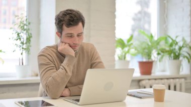 Ofiste dizüstü bilgisayarla otururken uyuklayan yorgun adam