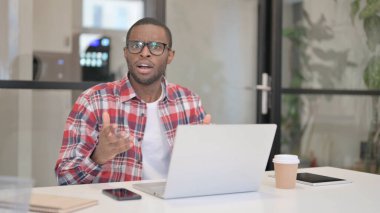 Dizüstü bilgisayar kullanırken kameraya bakan Afrikalı Adam
