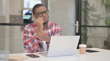 Dizüstü bilgisayar kullanırken bileği ağrıyan Afrikalı adam