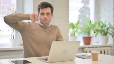 Ofiste dizüstü bilgisayar kullanırken Başparmakları Aşağı İşaretini Gösteren Adam