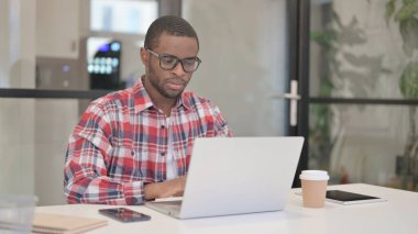 Ofisteki dizüstü bilgisayarda çalışan Afrikalı Adam