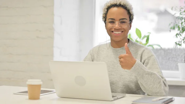 Mulher Africano mostrando polegares para cima assinar enquanto estiver usando laptop no escritório — Fotografia de Stock