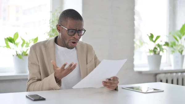 African Man Upset while Reading Documents in Office