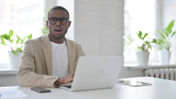 African Man känner sig chockad när du använder laptop i Office — Stockfoto