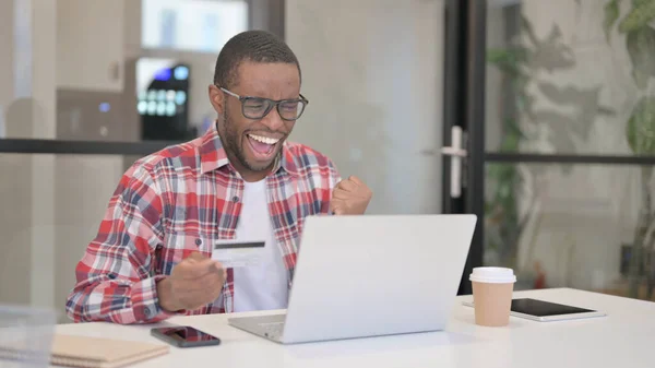 Afrikansk man gör framgångsrika online-betalning på laptop — Stockfoto