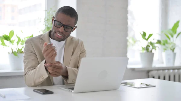 African Man having Wrist Pain while using Laptop in Office — Stockfoto