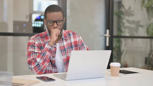 Hombre africano tosiendo mientras usa el ordenador portátil —  Fotos de Stock