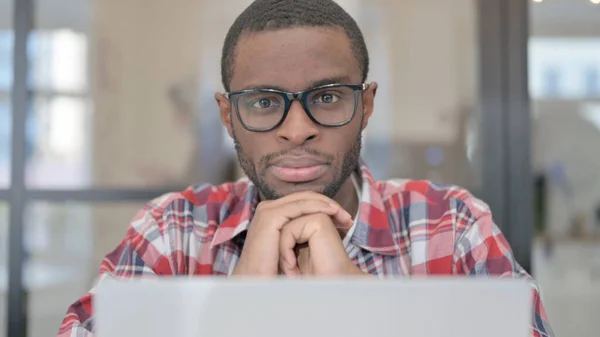 Närbild av afrikansk man med bärbar dator tittar i kameran — Stockfoto