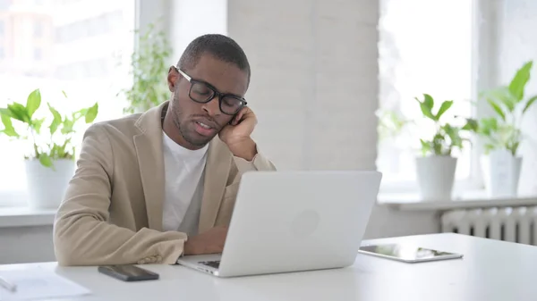 Trött afrikansk man tar en tupplur när du sitter i Office med laptop — Stockfoto