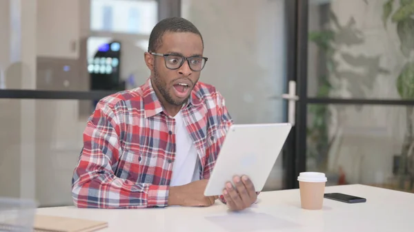 Hombre africano emocionado por ganar en línea en la tableta en la oficina —  Fotos de Stock