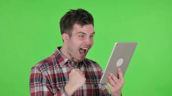 Retrato de un hombre joven celebrando el éxito en la tableta, Pantalla de croma verde —  Fotos de Stock