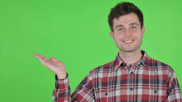 Portrait of Young Man Holding Product in Hand, Green Chroma Screen — 스톡 사진