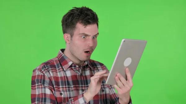 Porträt eines jungen Mannes, der auf Verlust auf Tablet, grünem Chrombildschirm reagiert — Stockfoto