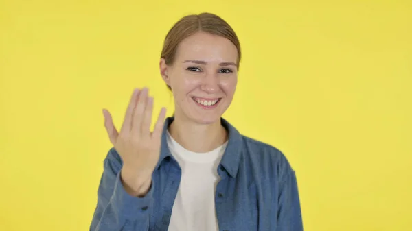 Junge Frau zeigt auf Kamera und lädt auf gelbem Hintergrund — Stockfoto