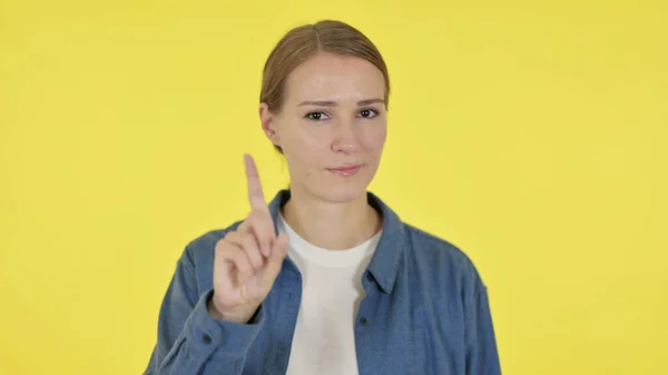 Giovane donna che mostra nessun segno da dito su sfondo giallo — Foto Stock