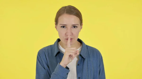 Junge Frau mit Finger auf Lippen, Schweigegelb — Stockfoto