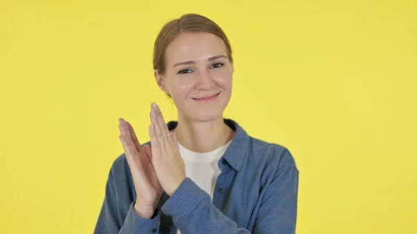 Ung kvinna klappar, applåderar på gul bakgrund — Stockfoto