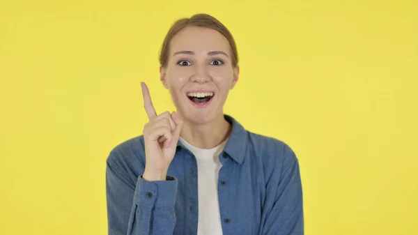 Umtriebige junge Frau bringt Idee auf den gelben Hintergrund — Stockfoto