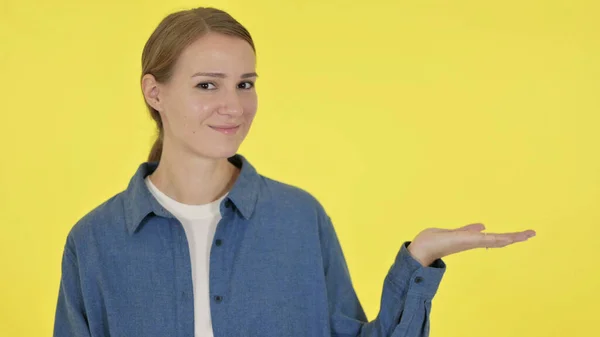 Молода жінка тримає продукт в руці на жовтому тлі — стокове фото