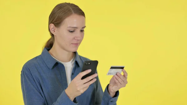 Mujer joven con éxito Compras en línea en Smartphone sobre fondo amarillo —  Fotos de Stock