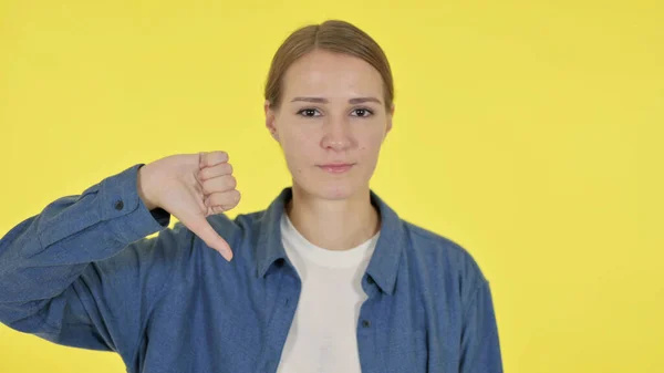Pollici giù gesti da giovane donna su sfondo giallo — Foto Stock