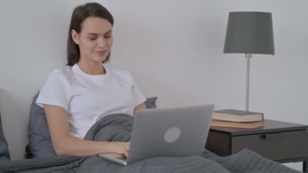 Женщина работает на ноутбуке в постели — стоковое видео
