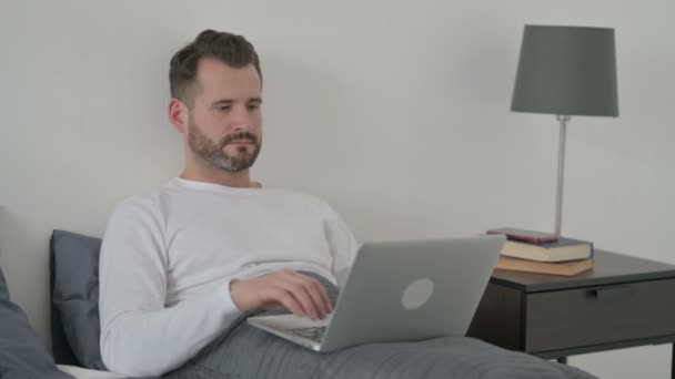 Man aan het werk op laptop in bed — Stockvideo