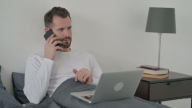 Dizüstü bilgisayarlı bir adam Smartphone 'da konuşuyor. 