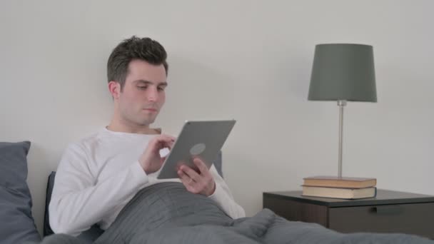 침대에 앉아 타블렛을 사용하는 사람 — 비디오