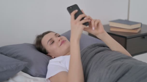 Женщина с помощью смартфона во время сна в постели — стоковое видео