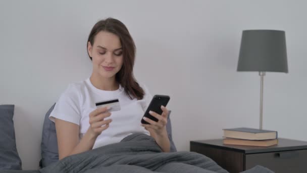 Женщина делает онлайн оплату на смартфоне в постели — стоковое видео