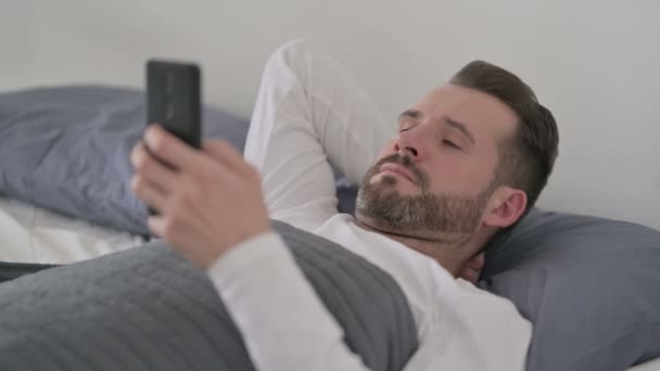 躺在床上用智能手机的人 — 图库视频影像