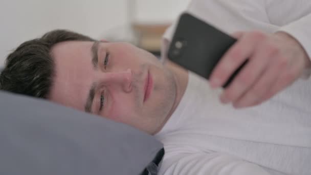 男人睡床的时候用智能手机，关门 — 图库视频影像