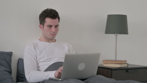 Mann mit Laptop hat Kopfschmerzen im Bett — Stockvideo