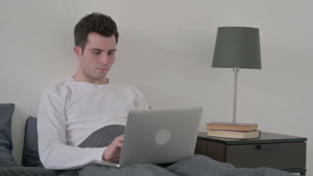 有背痛的男人在床上的笔记本电脑上工作 — 图库视频影像