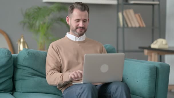 Людина працює на ноутбуці на софі — стокове відео